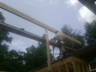 Carpenter setting a ridge beam over a new addition frame — Ice Dam Removal by Roofing Brothers in Mc Bee
