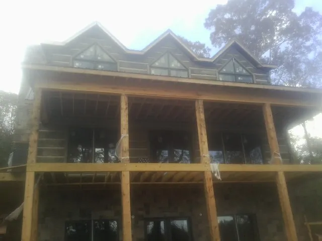 Dormers and porch framing on a large log home under construction — Roof Coating work by our crew in Mc Bee