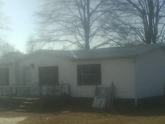 New metal roof on a white painted brick home on a foggy morning in Mc Bee