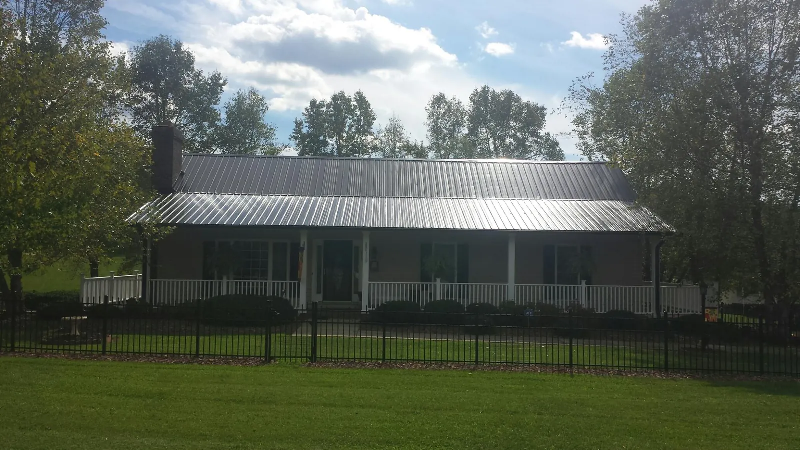 Gray metal roof on a brick ranch with a full width front porch — Gutter Guard Installation work by our crew in Mc Bee