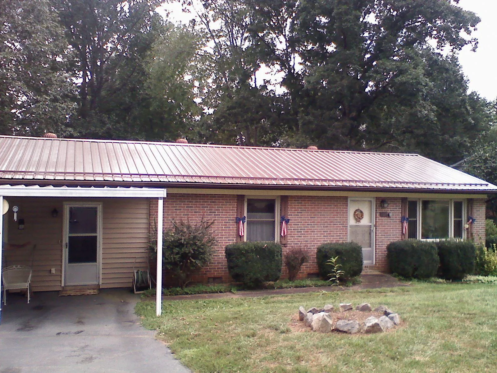 Bronze metal roof and carport on a brick ranch home — Roof Repair work by our crew in Mc Bee